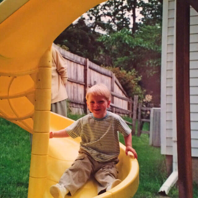 Young Alex going down a yellow slide